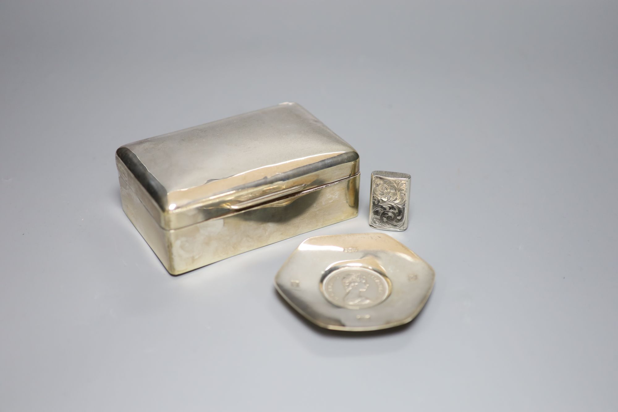 A silver cigarette box (marks rubbed), 14cm, a modern silver commemorative dish and a silver vesta case.